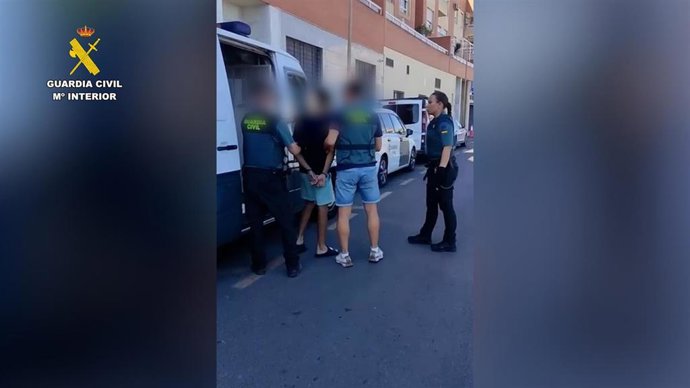 Uno de los detenidos, custodiado por agentes de la Guardia Civil en Roquetas de Mar (Almería).