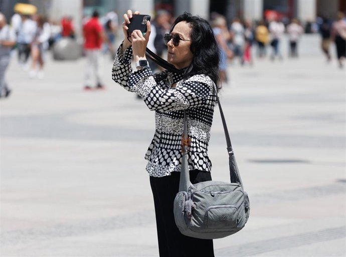 Archivo - Una turista toma fotografías en la Puerta del Sol