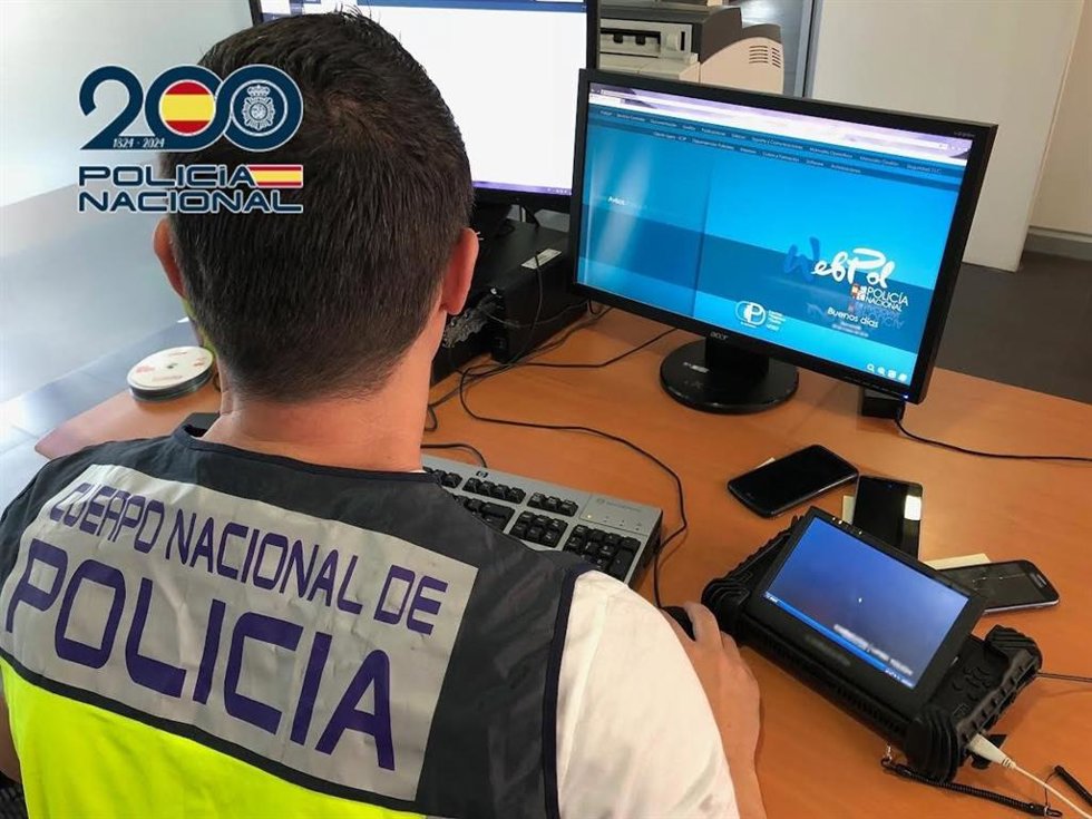 Archivo - Imagen de archivo de un agente de Policía Nacional frente a un ordenador. 