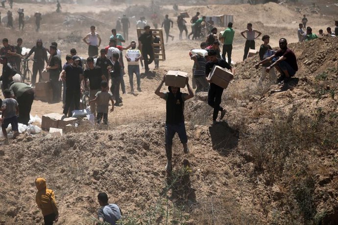 Archivo - Imagen de archivo de un grupo de palestinos tras recibir paquetes de ayuda a manos de la Fundación Humanitaria de Gaza.
