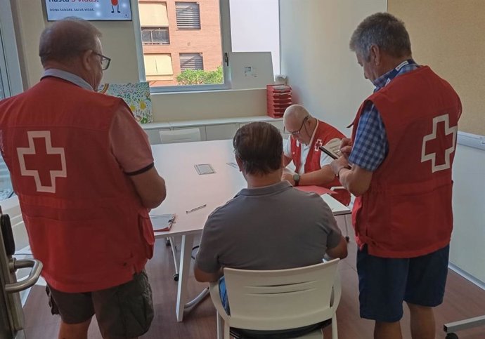 Voluntarios de Cruz Roja entregan los vales.