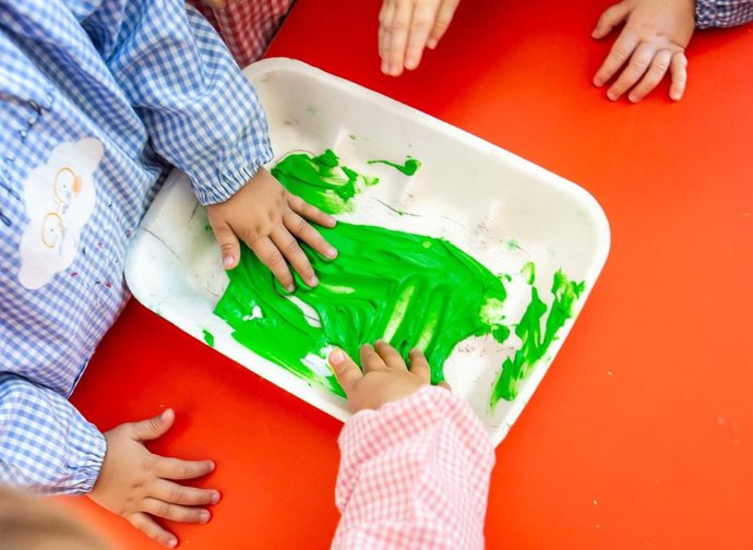 Archivo - Dos niños con una bandeja de pintura en un colegio.