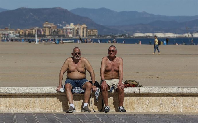 Archivo - Dos hombres toman el sol en la playa de La Malvarrosa, a 10 de marzo de 2023, en Valencia
