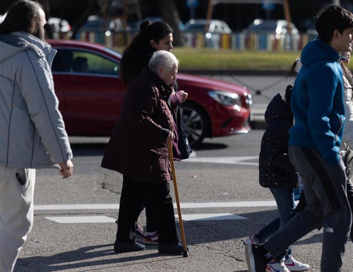 Archivo - Una mujer cuida de otra mujer mayor que pasea con bastón.
