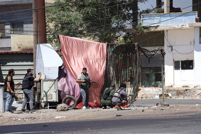 SWEIDA, 18 de julho de 2025 -- Combatentes tribais se protegem durante confrontos na cidade de Wolgha, na zona rural ocidental de Sweida, sul da Síria, em 18 de julho de 2025. Na sexta-feira, as autoridades interinas da Síria fizeram um apelo à contenção 