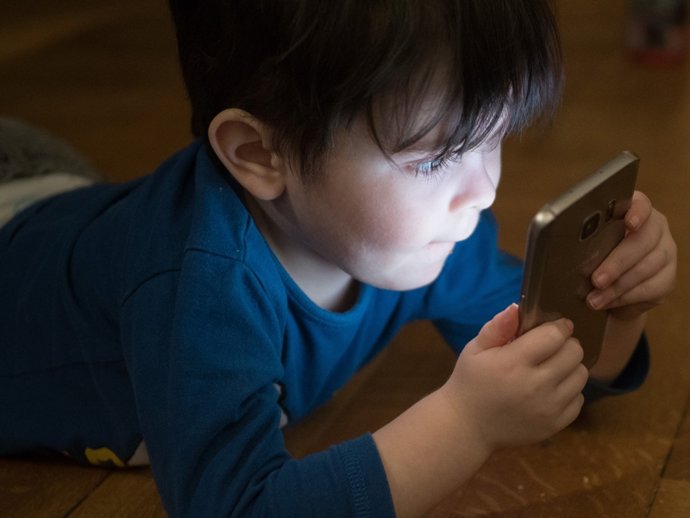 Un niño ante la pantalla de un teléfono móvil