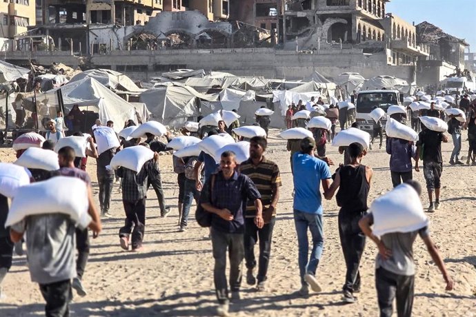 TERRITÓRIOS PALESTINOS, GAZA - 2 DE AGOSTO DE 2025: Palestinos com sacos de ajuda humanitária em Zikim, no norte de Gaza