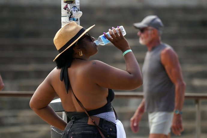 Una mujer bebiendo agua un día de calor. 