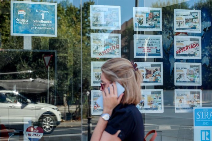Archivo - Una mujer camina frente a un escaparate de anuncios de viviendas, en Madrid (España)
