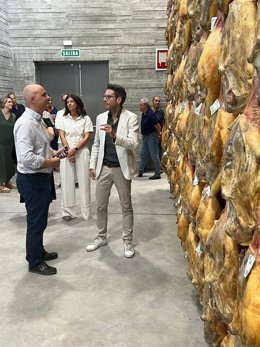 Un técnico de la fábrica jamonera (dcha) muestra productos finales al viceconsejero Jorge LLorente