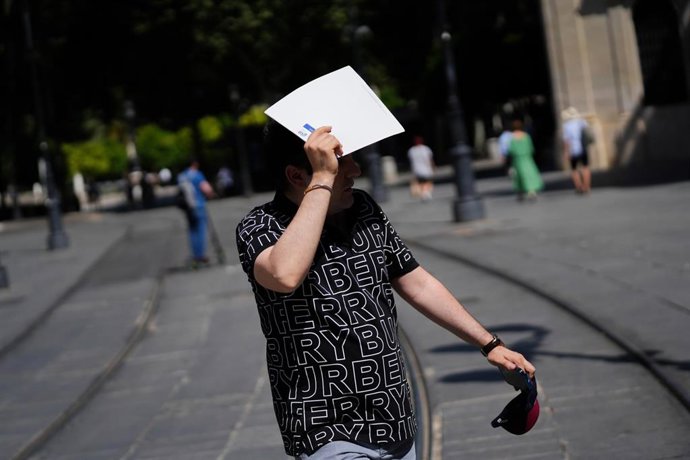 Archivo - Un hombre se protege del sol con una carpeta