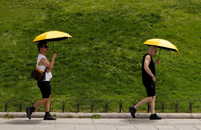 Archivo - Varias personas se resguardan del sol bajo un paraguas, a 18 de julio de 2024, en Madrid (España). La primera ola de calor del verano pone hoy en aviso amarillo o naranja a casi toda España, con temperaturas que superarán los 40 grados en alguno