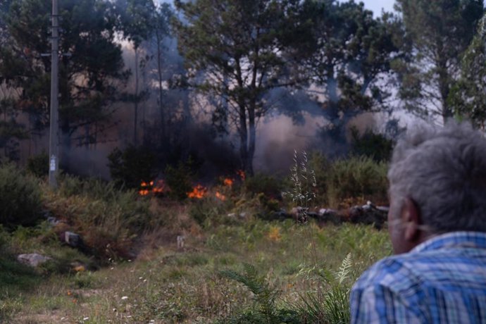 Uma pessoa observa o incêndio em 5 de agosto de 2025 em Ponteceso, Corunha, Galícia (Espanha). Um novo incêndio no município de Ponteceso, na Corunha, na terça-feira, forçou a evacuação dos moradores da paróquia de Corme Aldea. Fontes da Consellería d