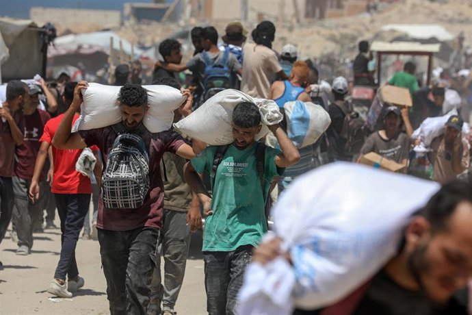 Archivo - Palestinos transportan sacos de harina que obtuvieron de camiones de ayuda humanitaria que entraron en Gaza a través del paso fronterizo de Zikim, en Yabalia, en el norte de la Franja de Gaza