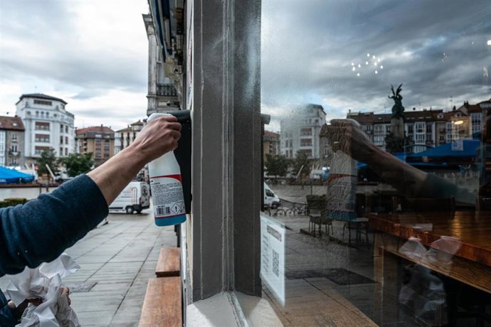 Archivo - Una camarera limpia el cristal de su cafetería 