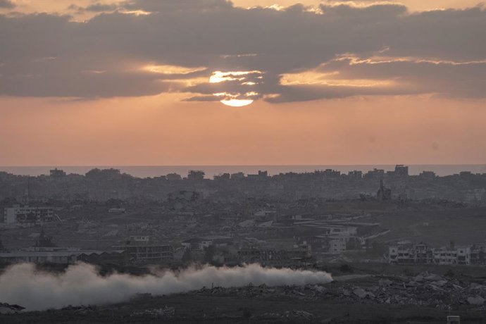 30 de julho de 2025, Israel, ---: O sol se põe sobre a Faixa de Gaza, enquanto a fumaça se arrasta atrás de um tanque israelense em movimento, visto do sul de Israel. Foto: Ilia Yefimovich/dpa