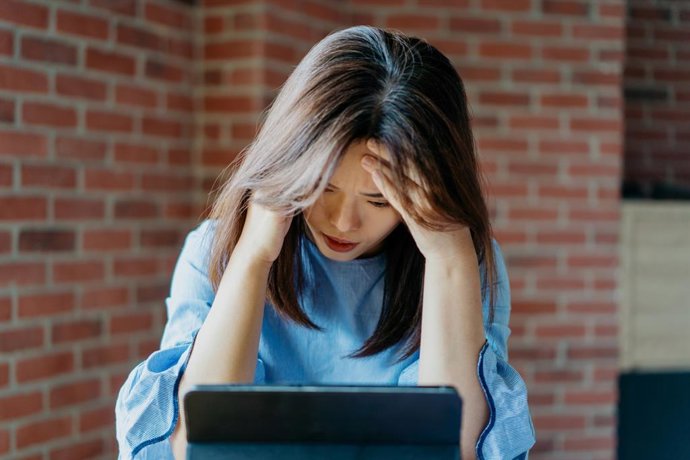 Archivo - Mujer trabajando, triste, deprimida, tablet