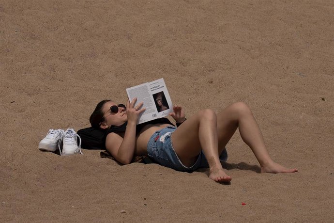 Archivo - Una mujer toma el sol en la playa de la Barceloneta, a 25 de abril de 2023, en Barcelona, Catalunya (España). 
