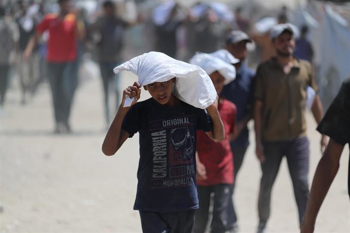 Un hombre palestino cargado con un saco de ayuda humanitaria en la Franja de Gaza
