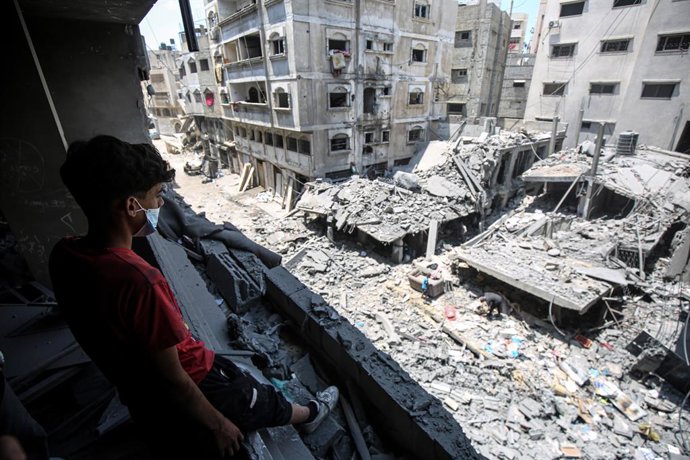 August 8, 2025, Gaza City, Gaza Strip, Palestinian Territory: A youth looks out carefully from a badly damaged building above the destruction at the site of a morning Israeli strike on a house, in Gaza City,.