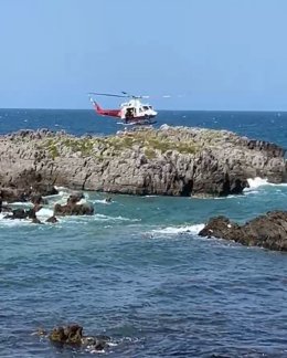Playa del Ris, en Noja. El helicóptero del Gobierno de Cantabria rescata a dos franceses, un hombre y una mujer de 20 años, atrapados en unas rocas al subir la marea