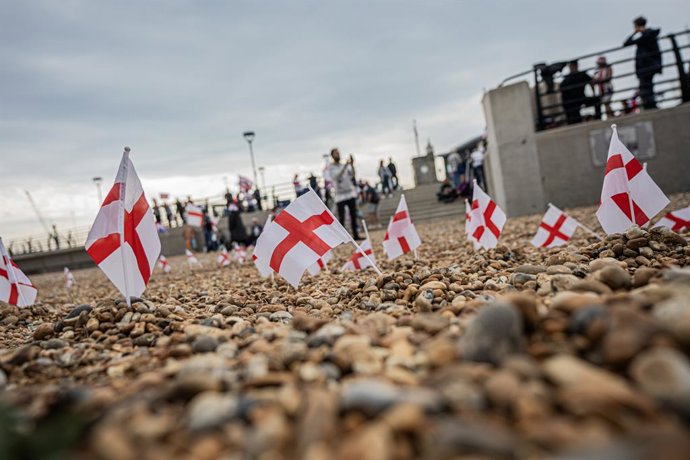 19 de julho de 2025, Dover, Reino Unido: Pequenas bandeiras de São Jorge fincadas na praia de pedra de Dover, do outro lado do canal de Calais. Uma pequena multidão de "patriotas" se reuniu na praia de Dover em um protesto contra a imigração, pedindo ao p