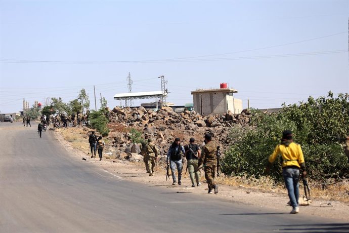 SWEIDA, July 18, 2025  -- Tribal fighters walk along a road near a frontline in the town of Wolgha, western countryside of Sweida, southern Syria, on July 18, 2025. The Syrian interim authorities on Friday issued a call for restraint amid escalating viole