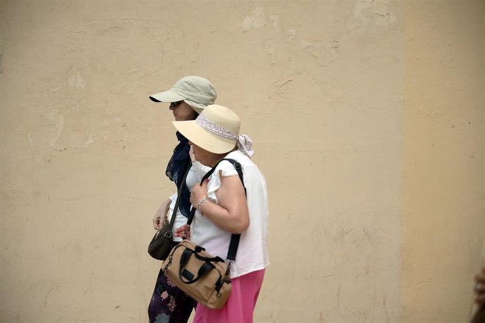 Archivo - Varias personas se protegen del sol en la calle.