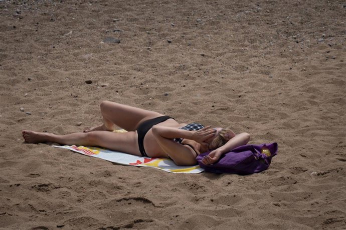 Archivo - Una mujer toma el sol en la playa