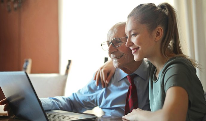 Una joven ayuda a una persona mayor a realizar una transacción digital.