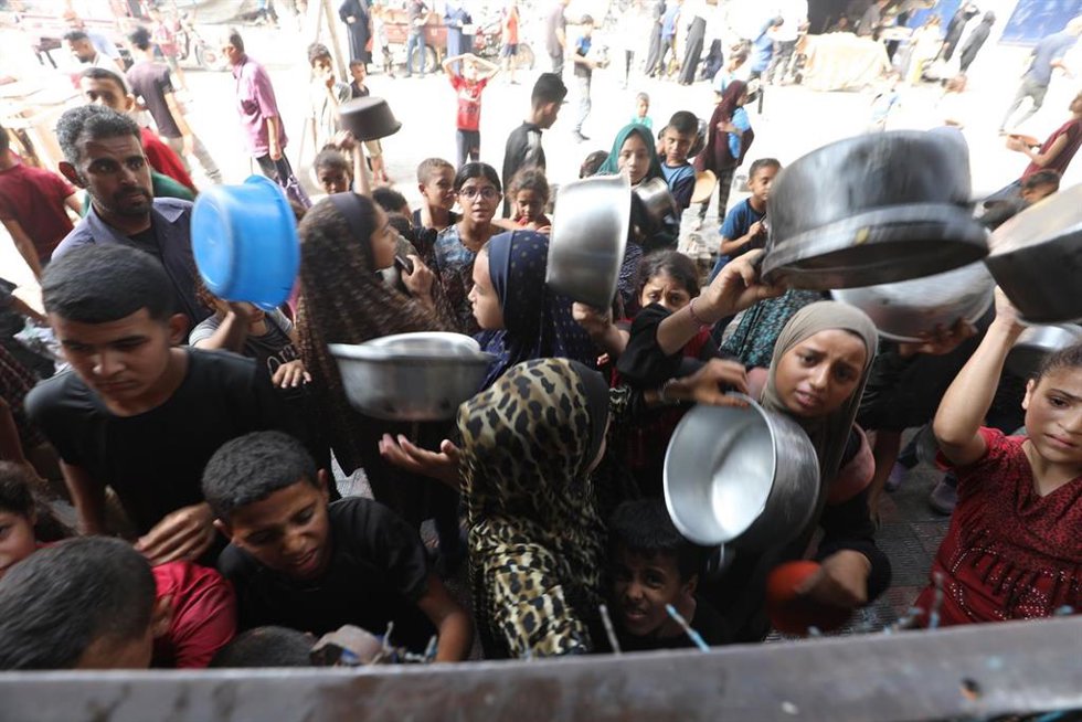 Un grupo de palestinos esperan para recibir comida en Bureij, en el centro de la Franja de Gaza