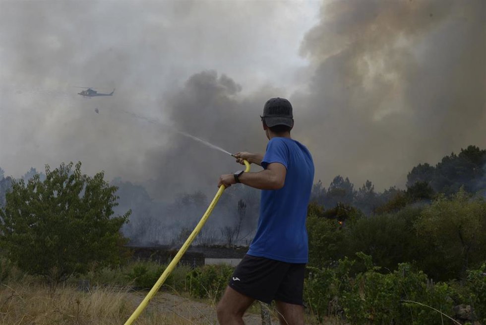 Una persona colabora en la extinción del incendio, a 12 de agosto de 2025, en Seixalbo, Ourense, Galicia.