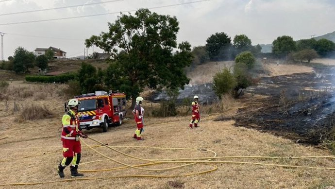 Bomberos extinguen un incendio en una pradería.