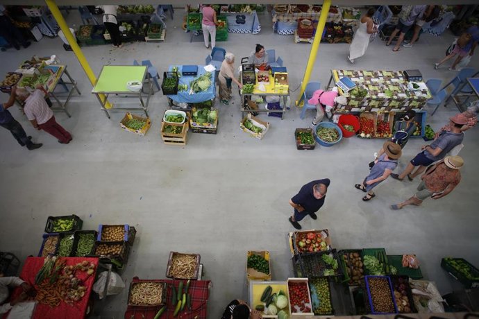 Archivo - Varias personas compran alimentos en un mercado.