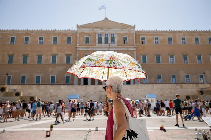FILED - 23 July 2025, Greece, Athens: A woman walks with an umbrella in front of the Greek parliament in the center of Athens. Photo: Socrates Baltagiannis/dpa