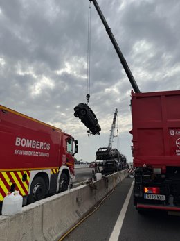 Os bombeiros removem o veículo híbrido queimado.