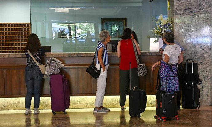 Turistas esperando para hacer el check in en un hotel.
