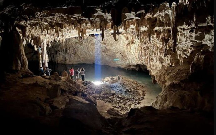 Turistas exploran la Cúpula de la Catedral, la cámara más grande de Grutas Tzabnah (Yucatán, México), y el origen de Tzab06-1. El pozo artificial "La Noria" ilumina ahora la cueva.