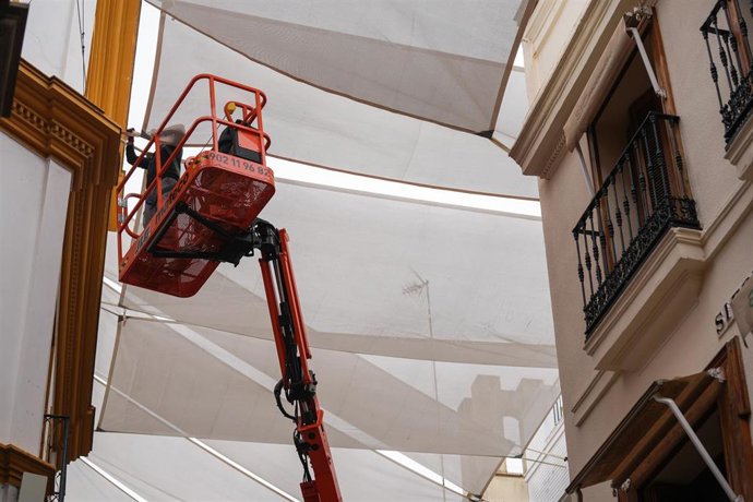Archivo - Archivo-Un operario coloca toldos en la calle Sierpes. 