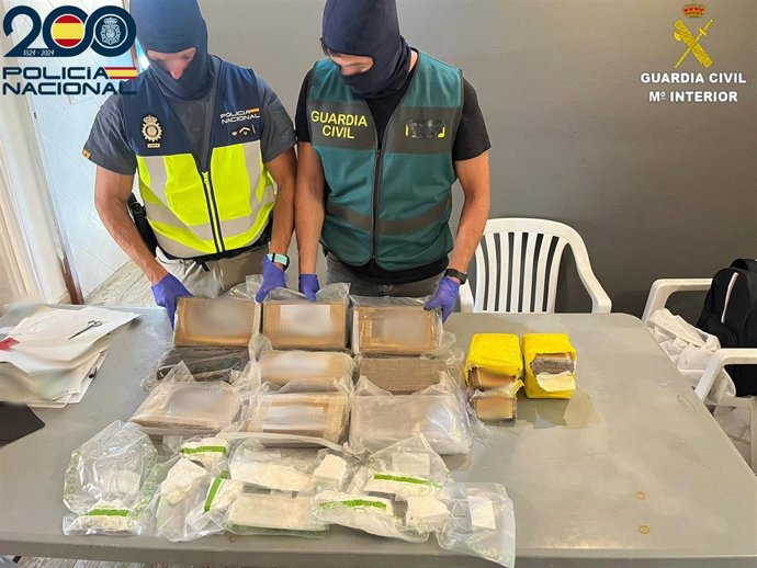 Un agente de la Policía Nacional y otro de la Guardia Civil, junto a parte de los estupefacientes intervenidos.