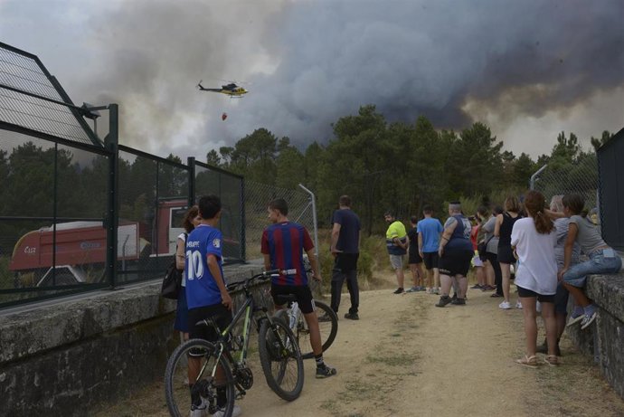 Vecinos y curiosos observan el fuego, a 12 de agosto de 2025, en Seixalbo, Ourense, Galicia (España). La Xunta ha decretado el nivel 2 de emergencia a nivel provincial en Ourense por grandes incendios que, en conjunto, calcinan alrededor de 4.330 hectárea