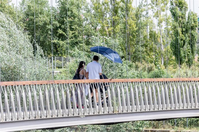 Dos personas se protegen del sol con una sombrilla, en Madrid (España). 