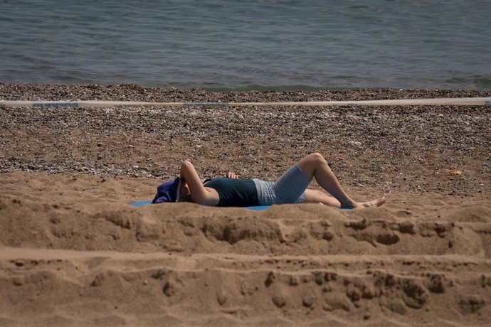 Archivo - Una mujer toma el sol en la playa de la Barceloneta, a 25 de abril de 2023, en Barcelona, Catalunya (España). 