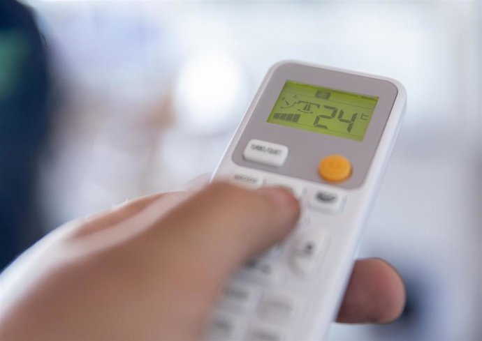 Una persona enciende un aire acondicionado,.