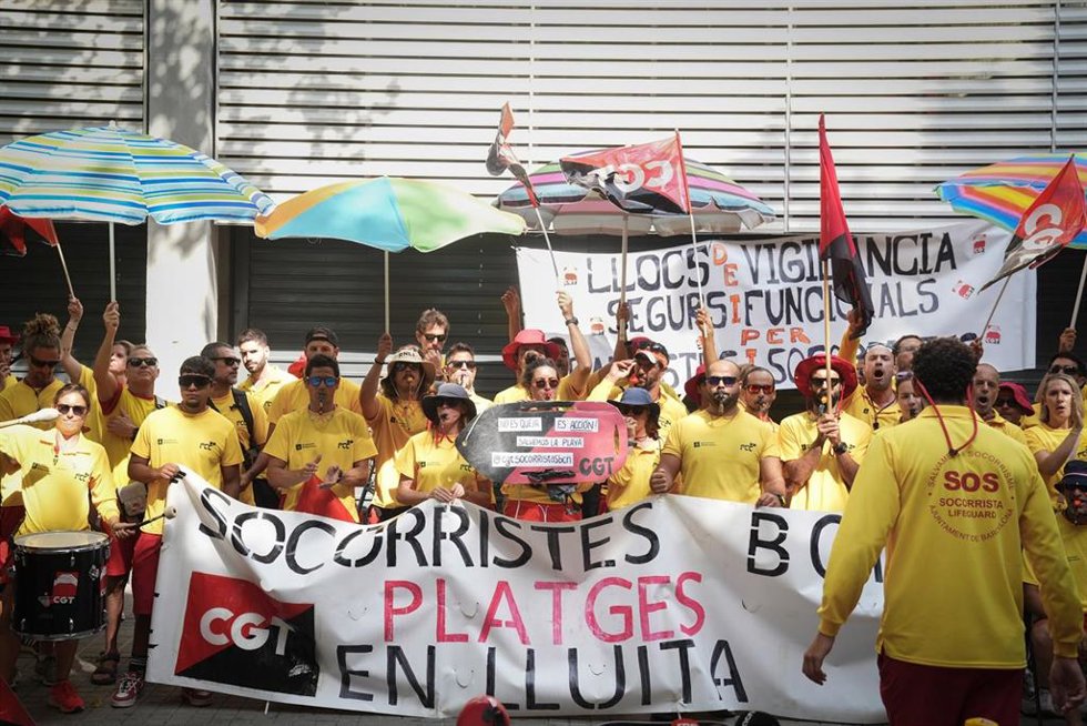 Varias personas protestan durante la huelga indefinida de los socorristas en Barcelona, frente a la sede del PSC, a 4 de agosto de 2025, en Barcelona, Catalunya (España).