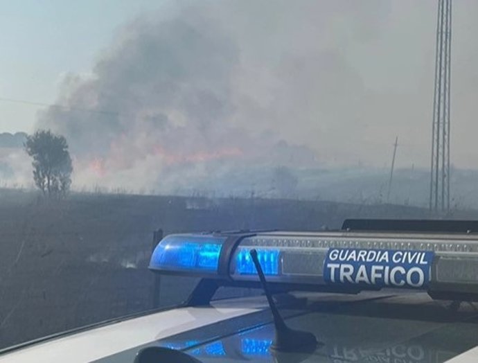 Un coche de la Guardia Civil de Salamanca con el incendio de El Payo de fondo.
