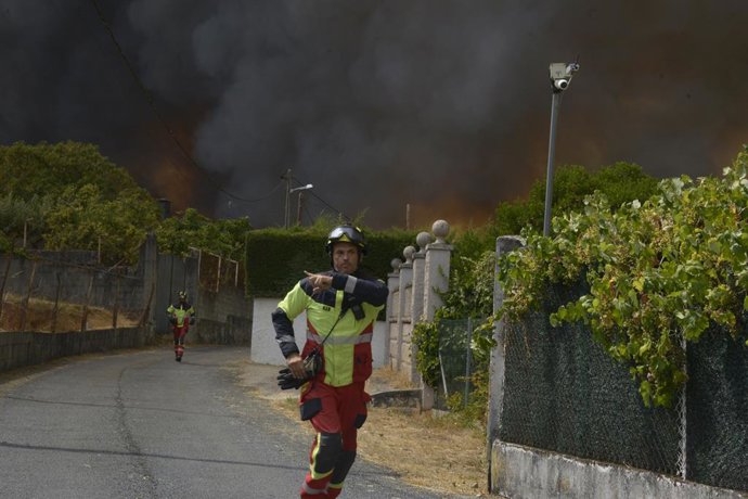 Dois bombeiros ajudam a extinguir um incêndio em 12 de agosto de 2025 em Seixalbo, Ourense, Galícia (Espanha). A Xunta decretou o nível 2 de emergência em nível provincial em Ourense devido a grandes incêndios que, juntos, queimaram cerca de