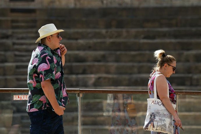Personas con ropa veraniega y sombreros.