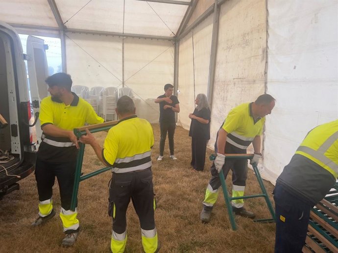 La alcaldesa en funciones, Eva María Pérez, y el concejal de Juventud y Participación Ciudadana, Nicolás Fernández, durante la descarga de material por parte de operarios municipales en la carpa de las fiestas de Lugo de Llanera.