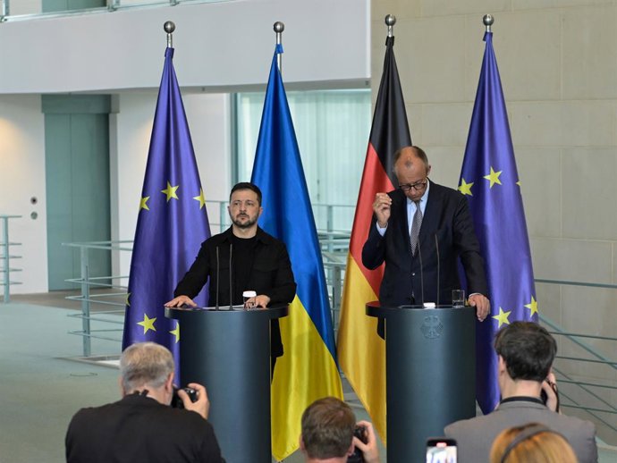 13 August 2025, Berlin: Ukrainian President Volodymyr Zelensky (L) and German Chancellor Friedrich Merz speak during a press conference after the virtual consultations between European heads of state and government in the Chancellery with a view to the me